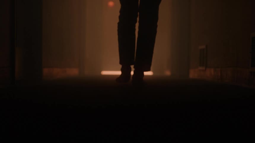 A persons feet and legs walk down a hallway