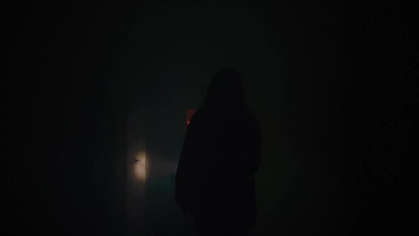 A lone figure moves through a foggy corridor flashlight cutting the darkness