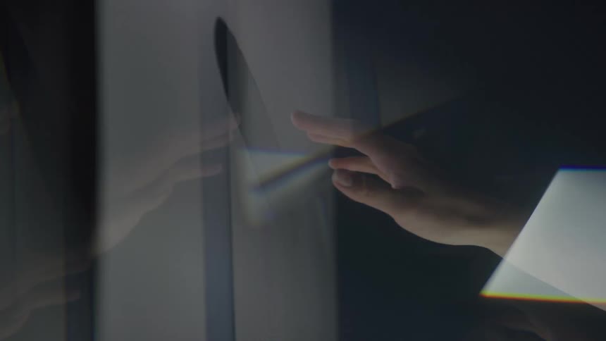 A hand reaches out to touch a reflective surface creating a faint mirrored image