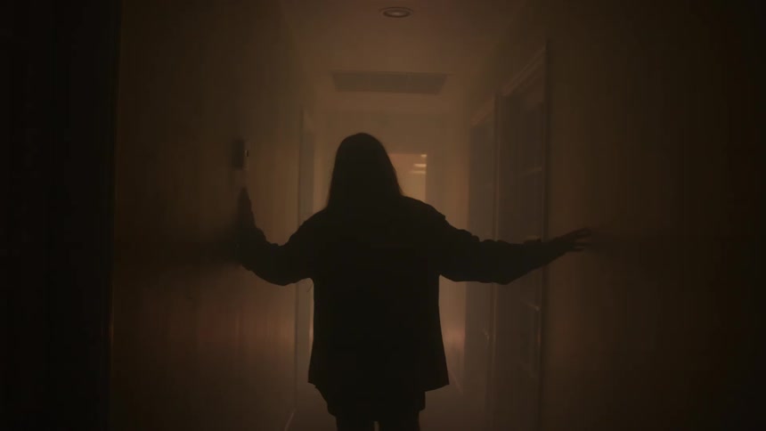 A persons silhouette stands in a hallway with arms outstretched