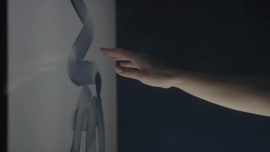 A hand gently touches a glowing screen with abstract shapes