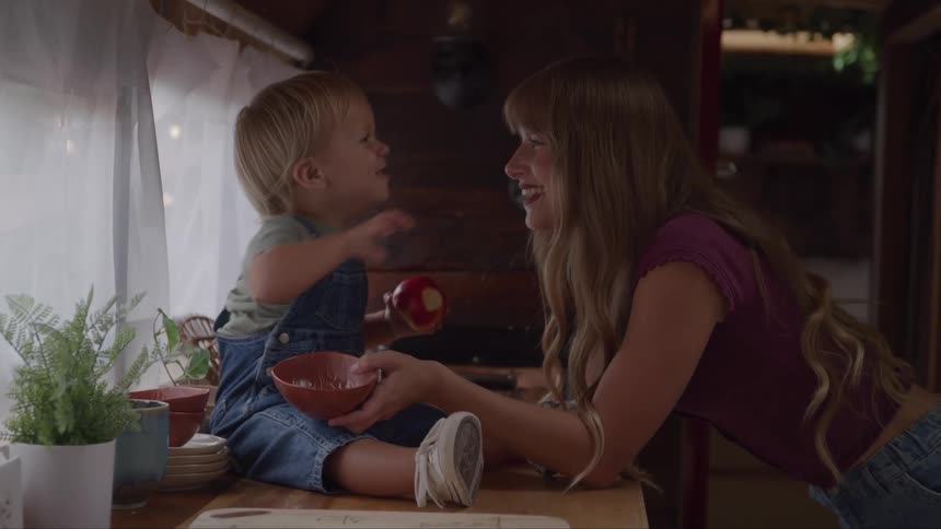 A woman smiles as a little boy playfully touches her face
