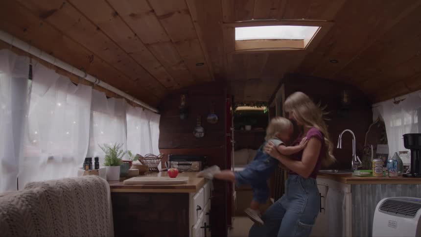 Woman plays lifting a child inside a cozy kitchen