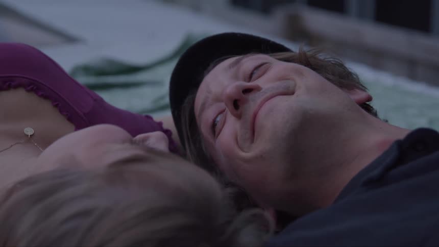 Man smiles lying next to a woman in a tender moment