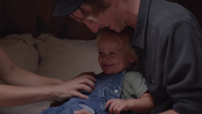 Child smiles while receiving affection from parents in a moment of tenderness