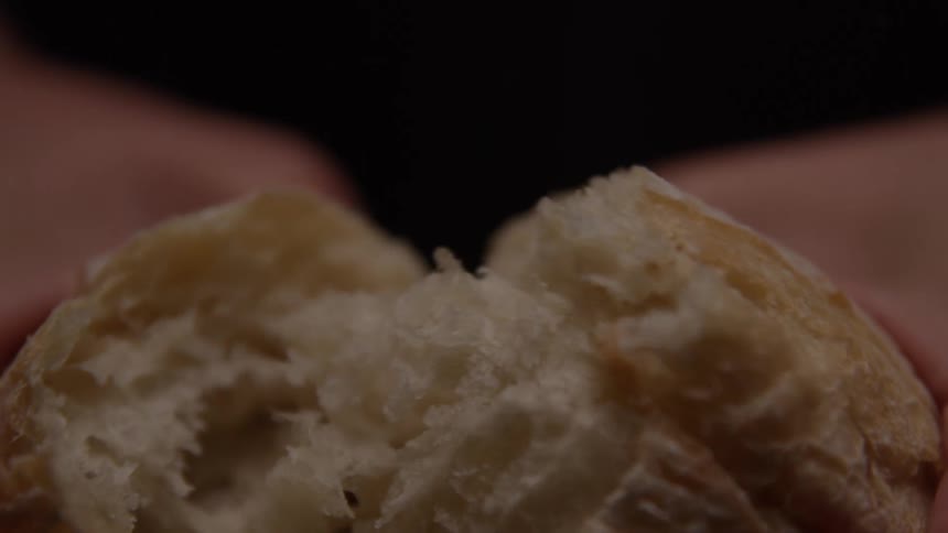 A roll is split open revealing soft crumb as steam escapes