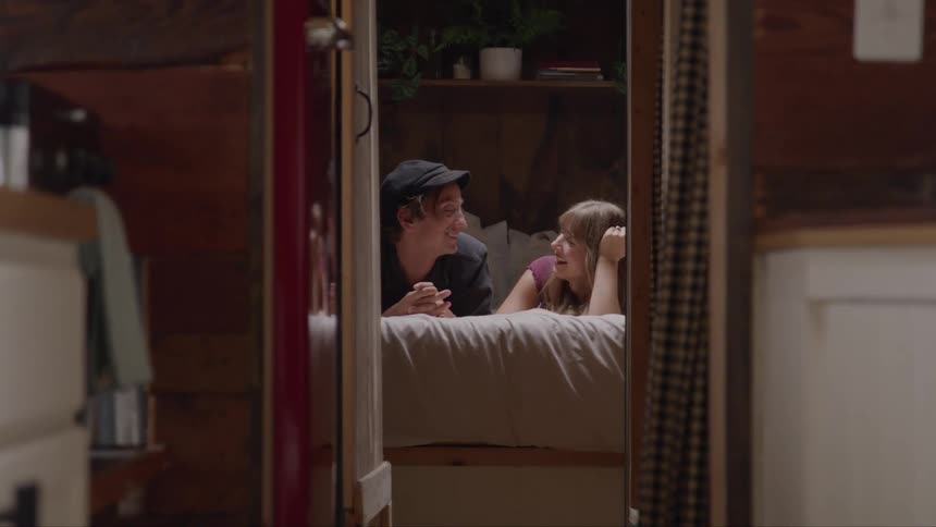 Couple lying on a bed smiles while sharing knowing looks