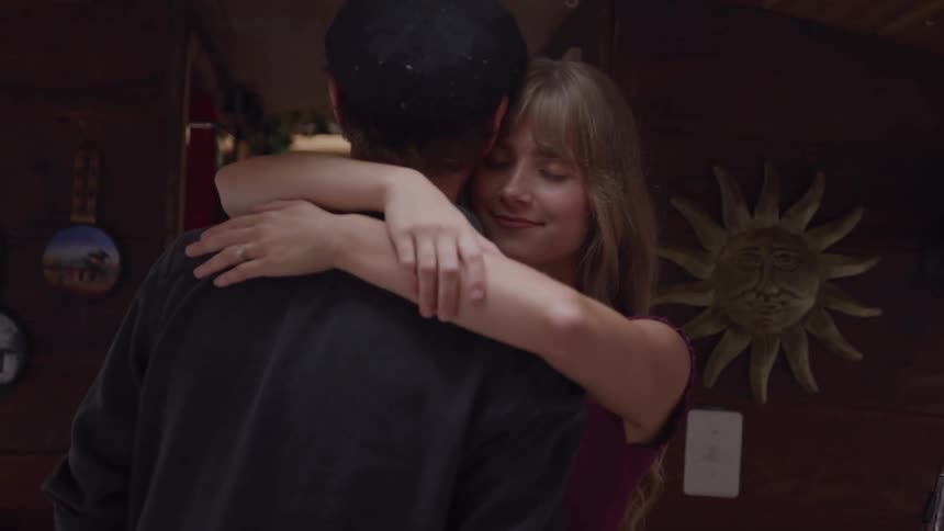 In a rustic kitchen a woman wraps her arms around a man as they slow dance
