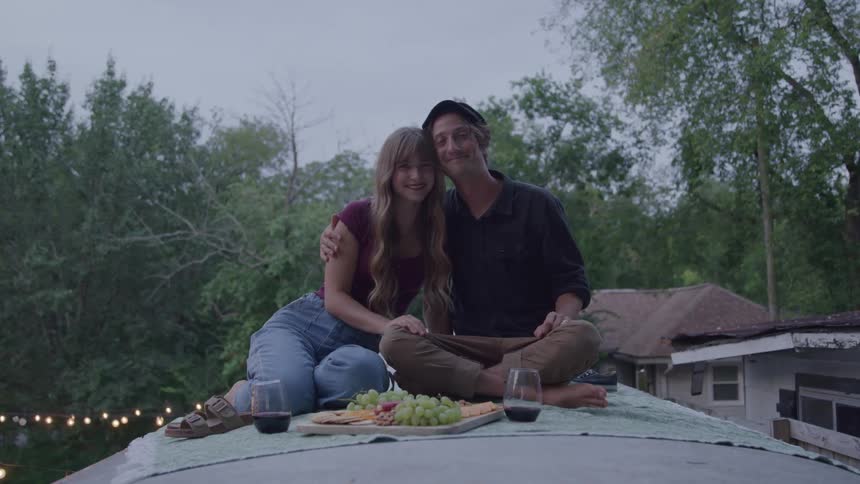 A couple enjoys a picnic date smiling together on a rooftop