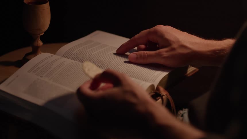 Hands guide through scripture next to a small cup