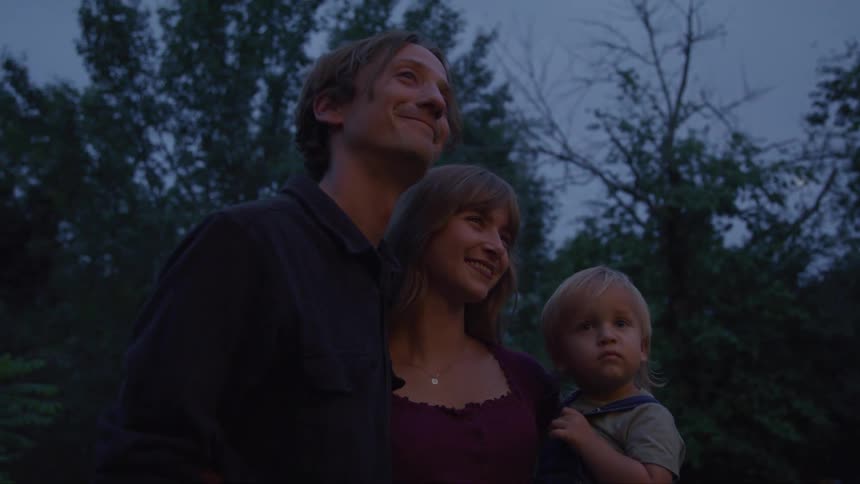 A small family looks up together at dusk sharing a quiet moment