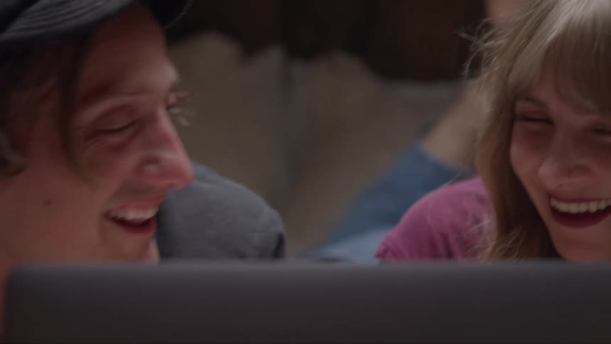 A young man and woman smile as the look at a laptop screen together