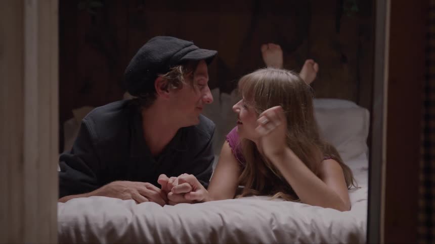 A couple shares a warm kiss while lying on a bed in the bedroom