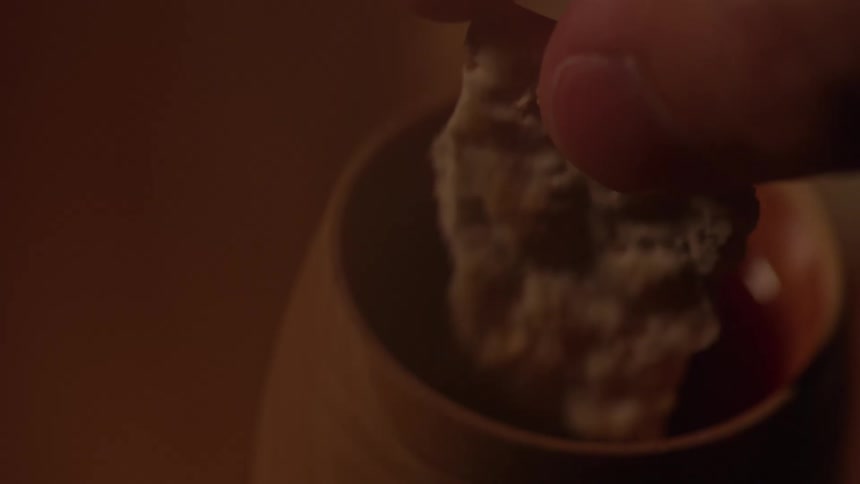 The video is a closeup shot of a hot liquid in a mug a hand is shown dunking a piece of toasted bread or similar baked good into the liquid