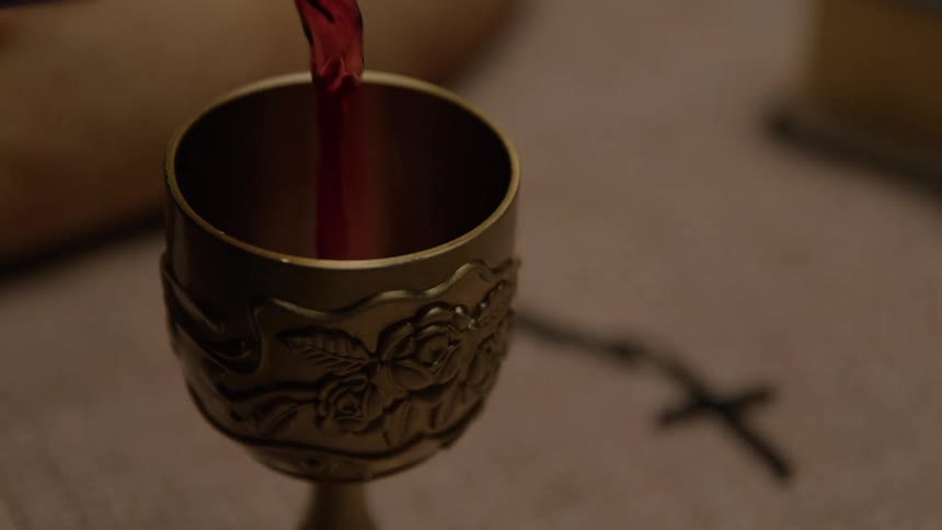 A chalice is filled with red wine on a table