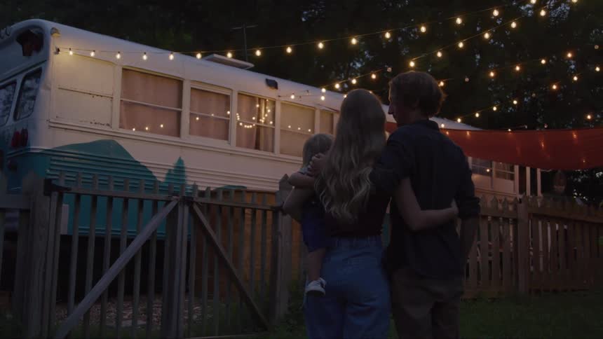 A family hug in the yard by the bus