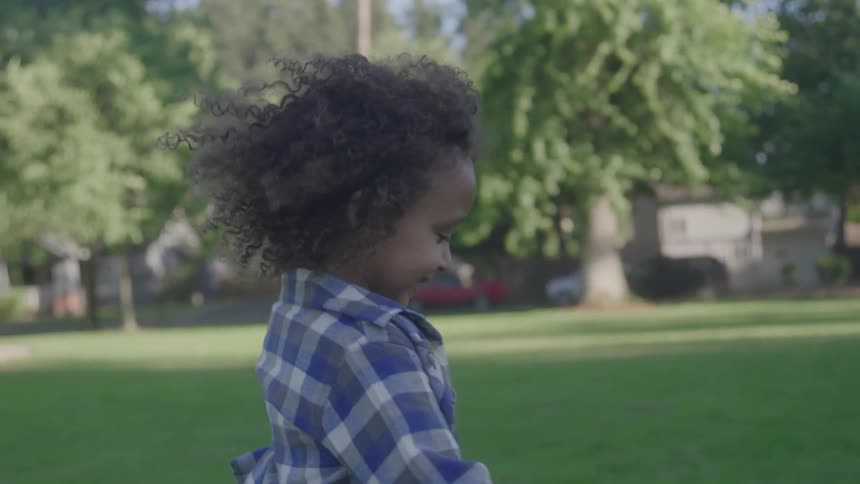 Close up of a female toddler running on a lawn outdoors during daytime