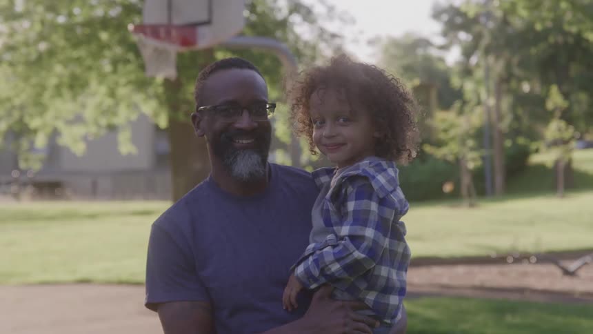 Portrait of a man carrying a girl child while standing outdoors during daytime