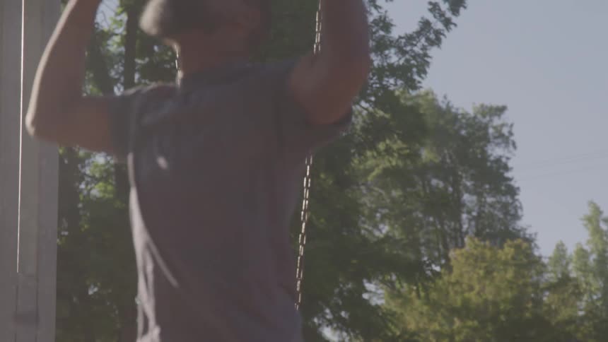 A father pushes his child on a swing in a sunny park