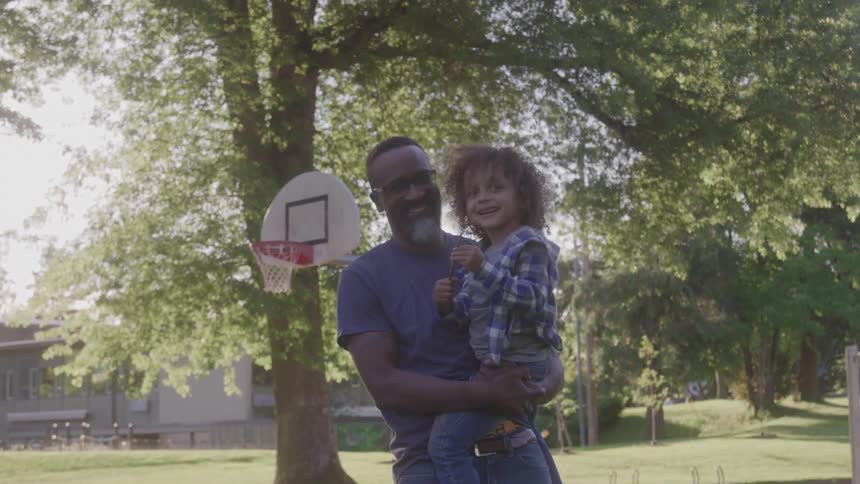Father holds his son while enjoying a sunny afternoon in the park