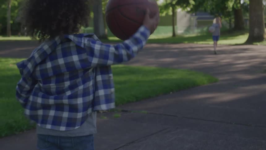 The child is bouncing the basketball in the park
