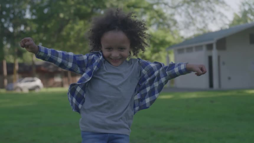 A child runs joyfully through a green park on a sunny day