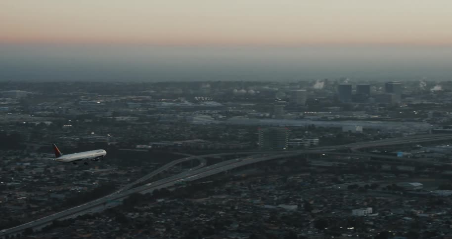 The video shows an airplane with the delta logo flying low over a city as it prepares to land the sky is a gradient of blue and pink suggesting it is either dusk or dawn