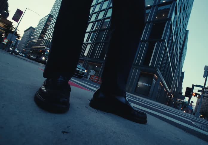 A persons feet standing on a city street near a crosswalk