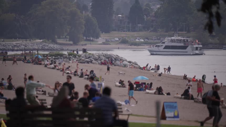 A body of water with a boat and a shore with people and trees in the background