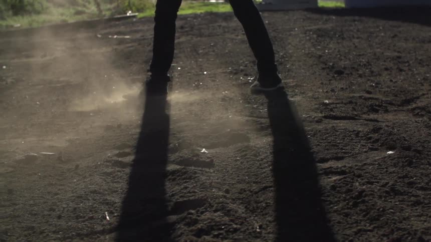 Feet kicking up dust in a dirt field
