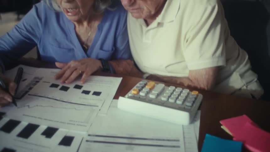 Elderly couple reviews financial charts together at the table