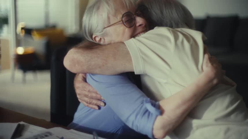 Elderly couple with glasses smiles and embraces affectionately