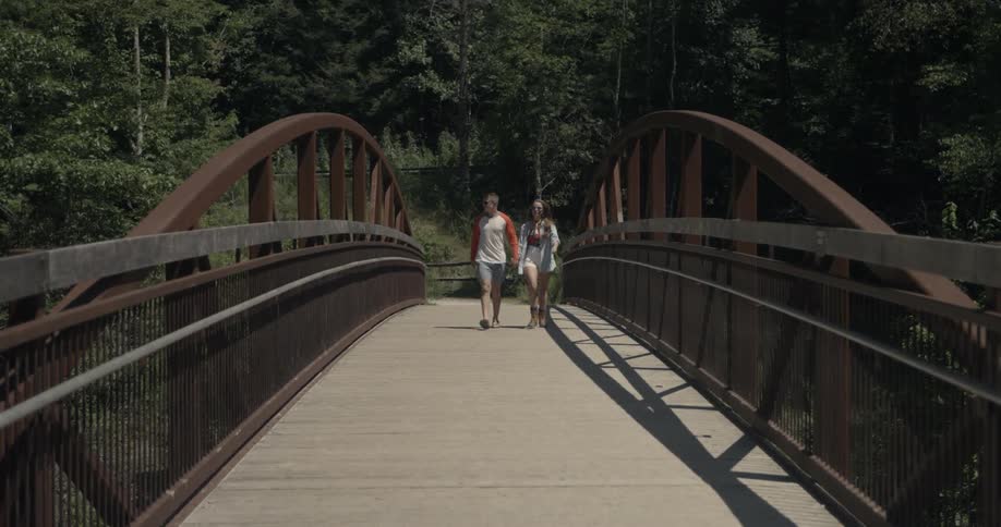 Two people walk across a wooden bridge