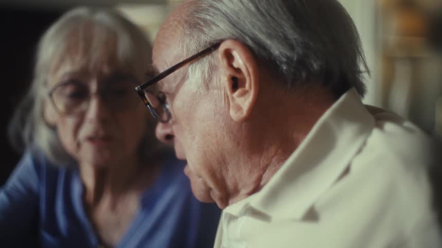 An elderly couple discusses something seriously in living room