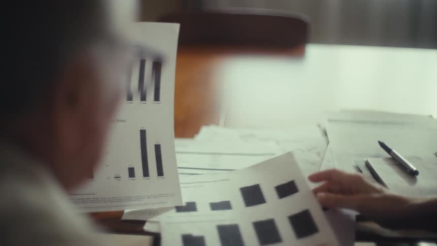 Two elderly people review a bar chart document together indoors