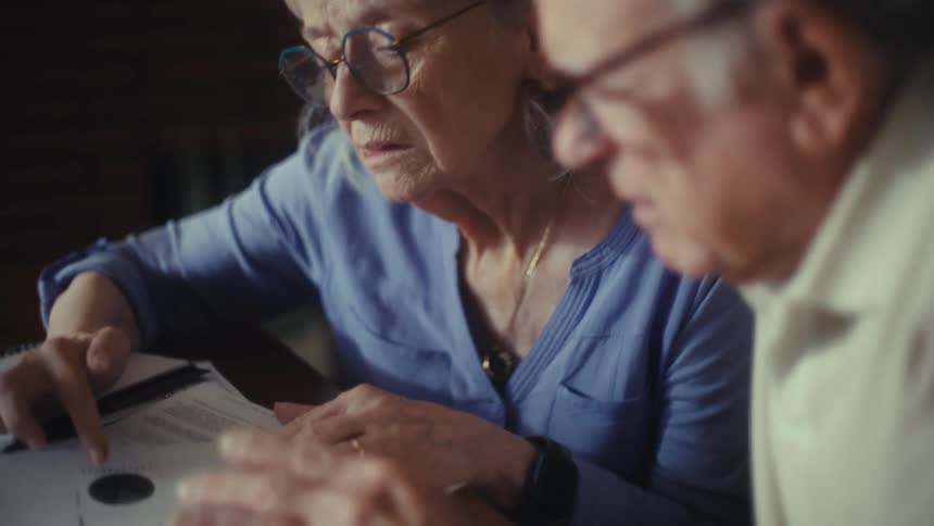 Elderly couple reviews documents on the table focused on financial notes