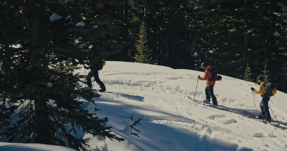 People climb the snowy mountain with skis and poles