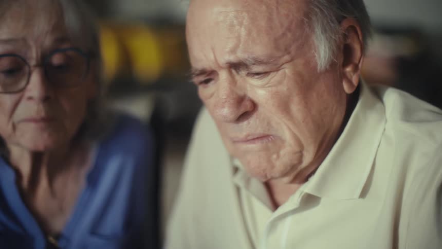 Elderly couple sitting at home looks through paperwork during the daytime