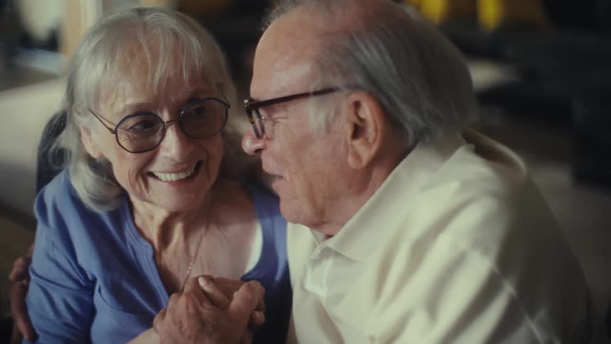 Elderly couple smiles and holds hands in a joyful moment