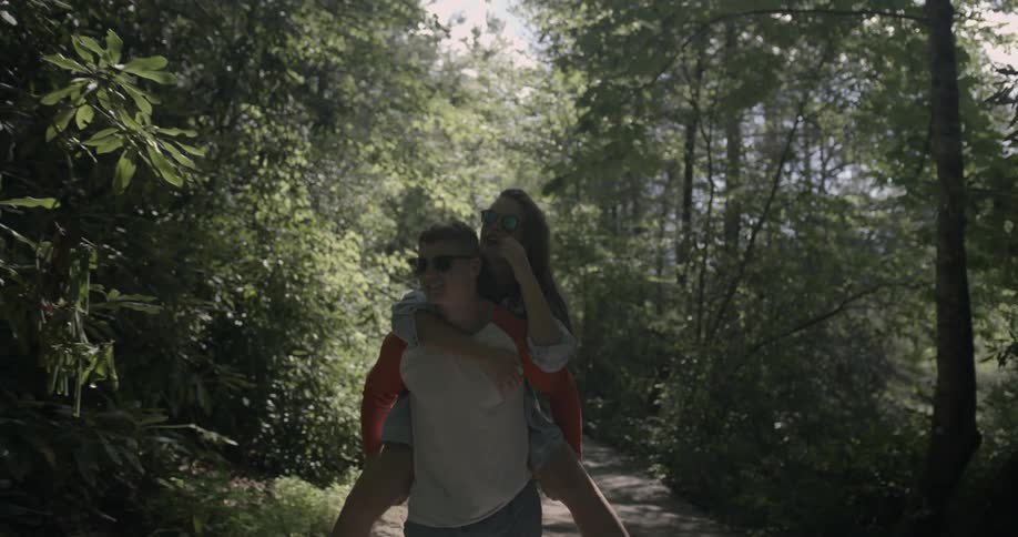 A man gives a woman a piggyback ride down a trail