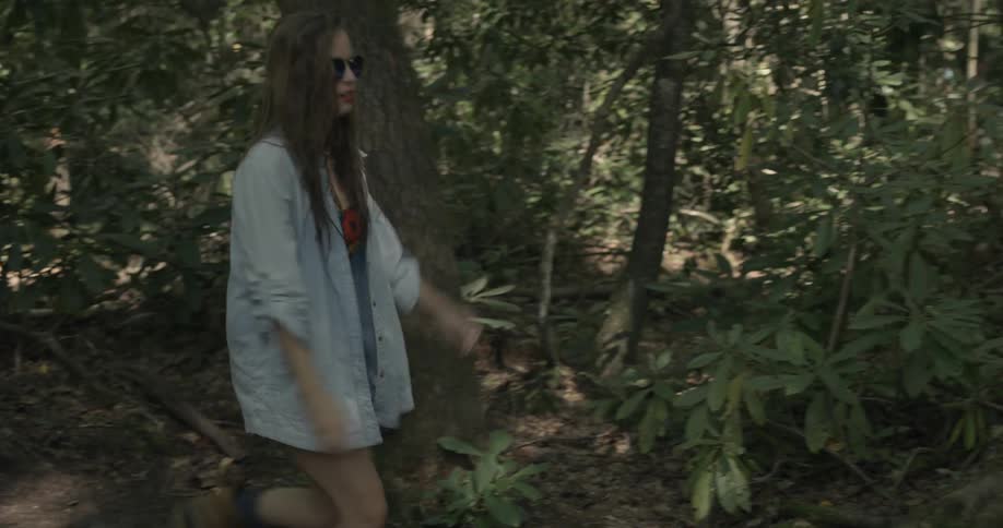 A man and woman walk downhill in the woods