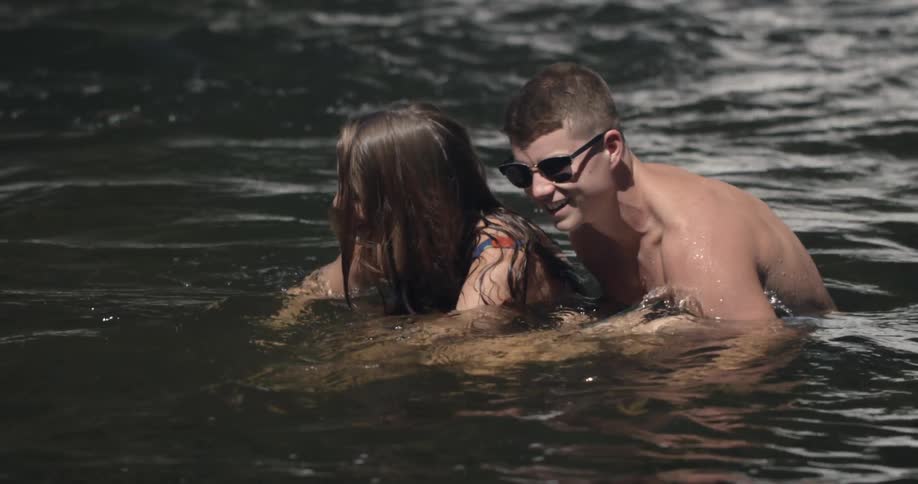 A woman moves over to a man laughing in the water