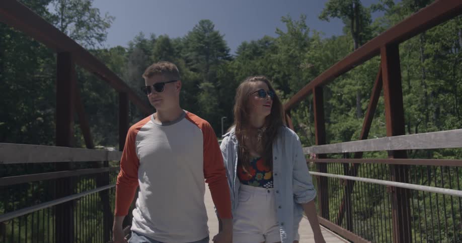 A man and woman walk together over a bridge