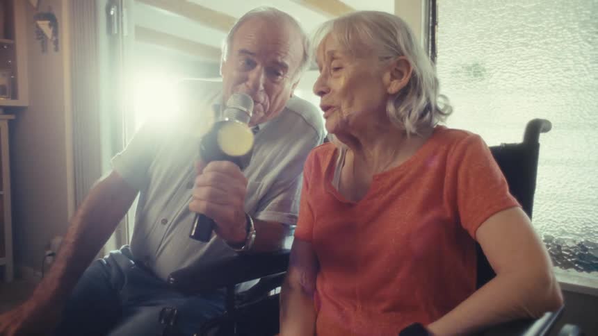 Elderly couple sing together with smiles at home