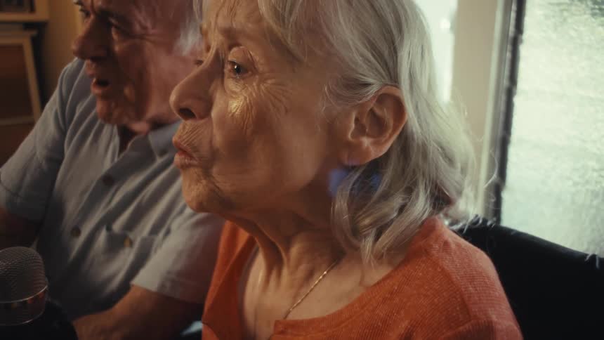 Woman sings joyfully beside her partner holding the microphone