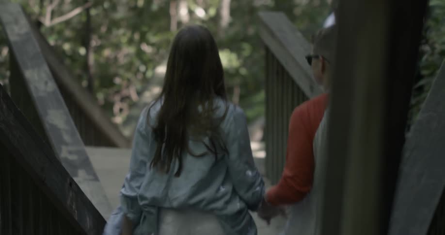 A man and woman hold hands walking down steps