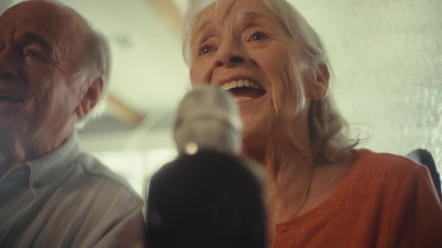 Elderly couple sings joyfully into the microphone with expressions of happiness