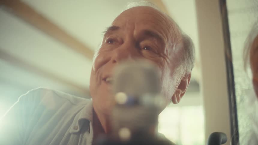 An elderly couple sings into a microphone excitedly having a fun time at midday
