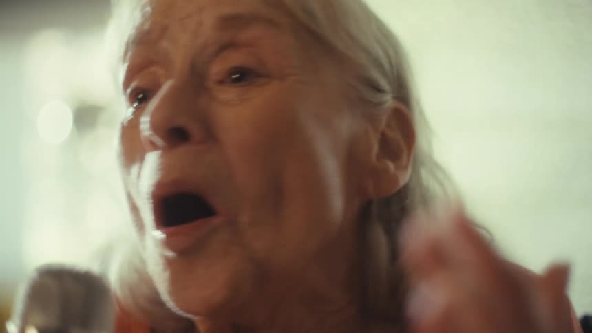 The woman waves her hand while singing into the microphone