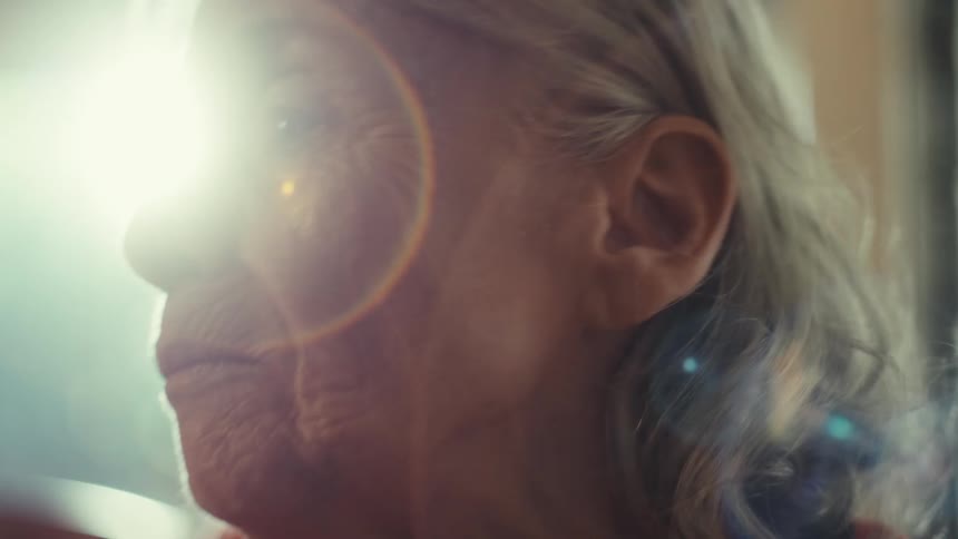 An elderly woman with an intense expression shouts or sings passionately into a microphone
